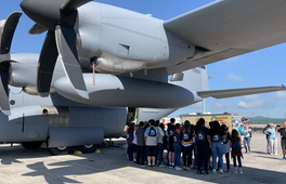 Photo of group of people beneath a plan
